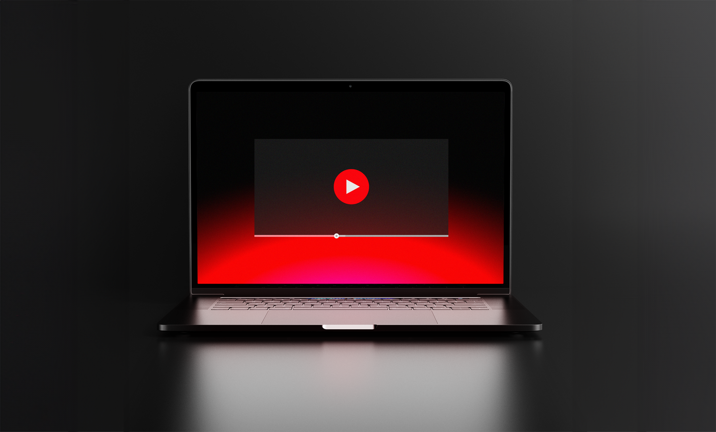 Laptop on a dark surface with a video player on the screen, highlighted by a red glow.